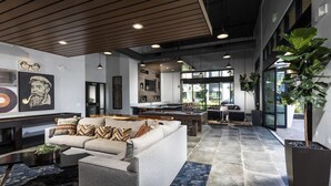 A spacious lobby with a modern design, featuring a large sofa, a pool table, and a dining area.