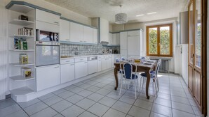 Una cocina moderna con armarios blancos, una mesa de comedor con sillas y un ventanal que proporciona luz natural.