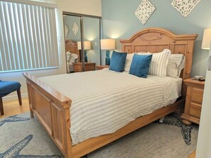 A bedroom with a wooden bed, bedside tables, a mirror, and a window with blinds. - The Dolphin: Beach~Workspace~W/D incl~PetsOK (Long Beach)