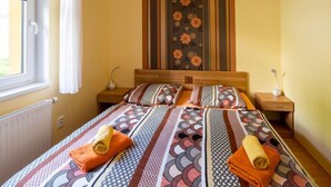 Ein Hotelzimmer mit einem Bett, zwei Nachttischen, einem fenster mit Vorhängen, einer Heizung und einer Wand mit Streifenmuster.