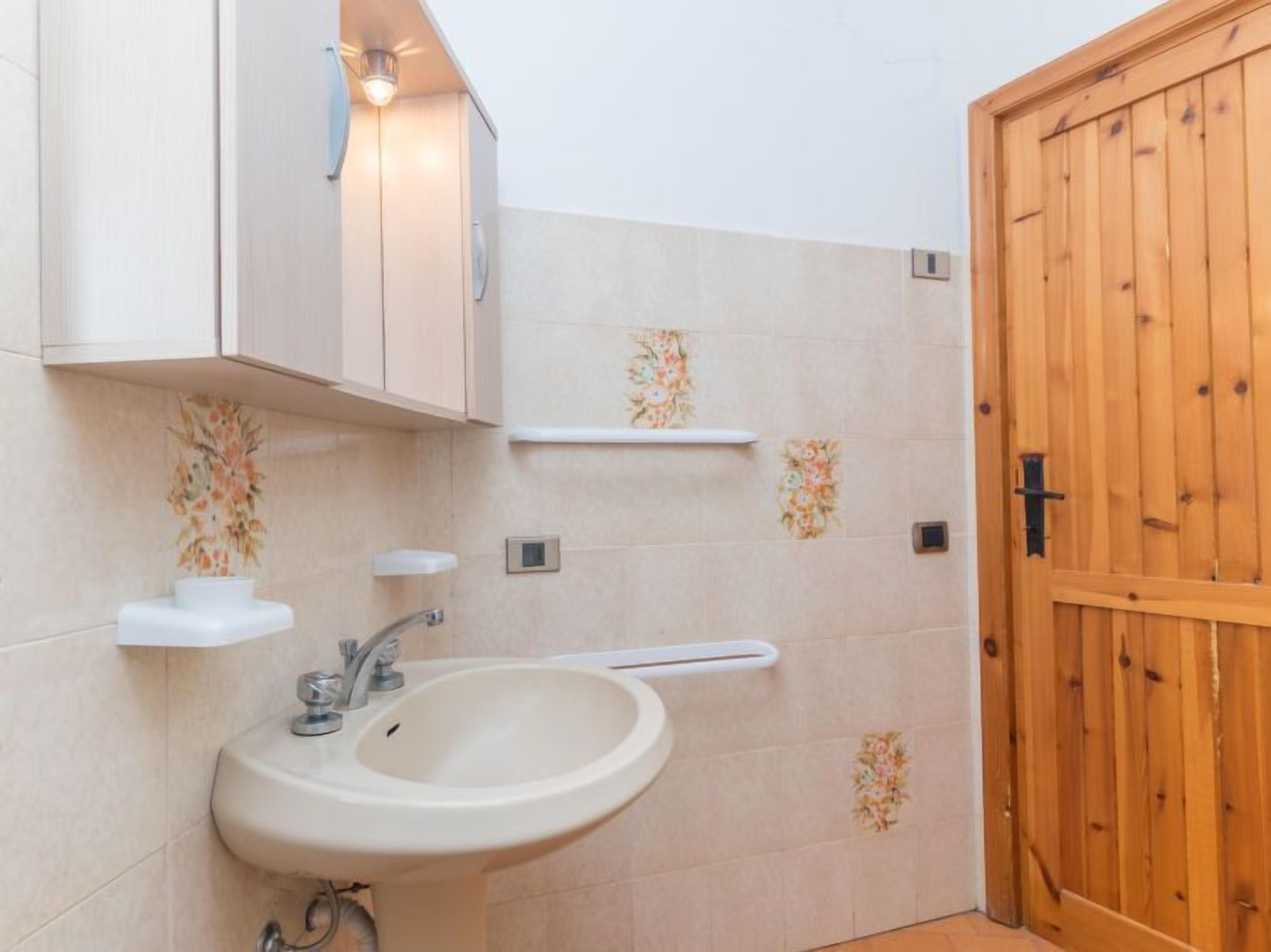 Un bany amb un lavabo, mirall i porta de fusta.