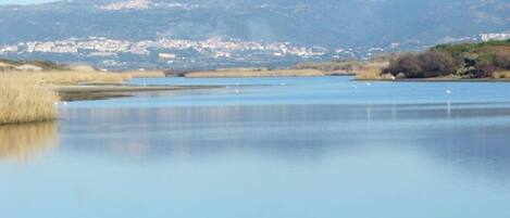 A calm lake with mountains in the background and a small town across the water.