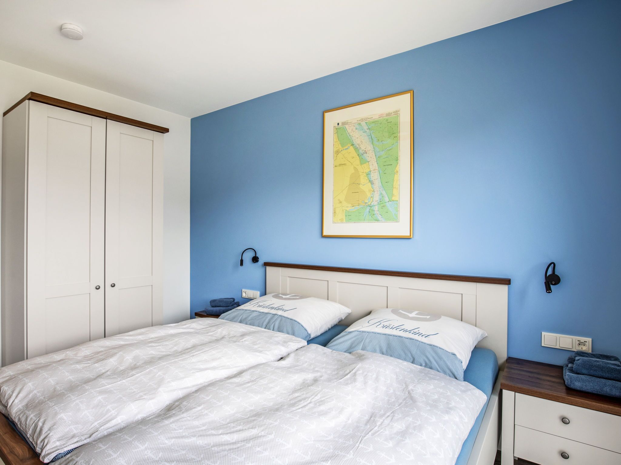Une chambre avec deux lits, une carte accrochée au mur et une armoire.