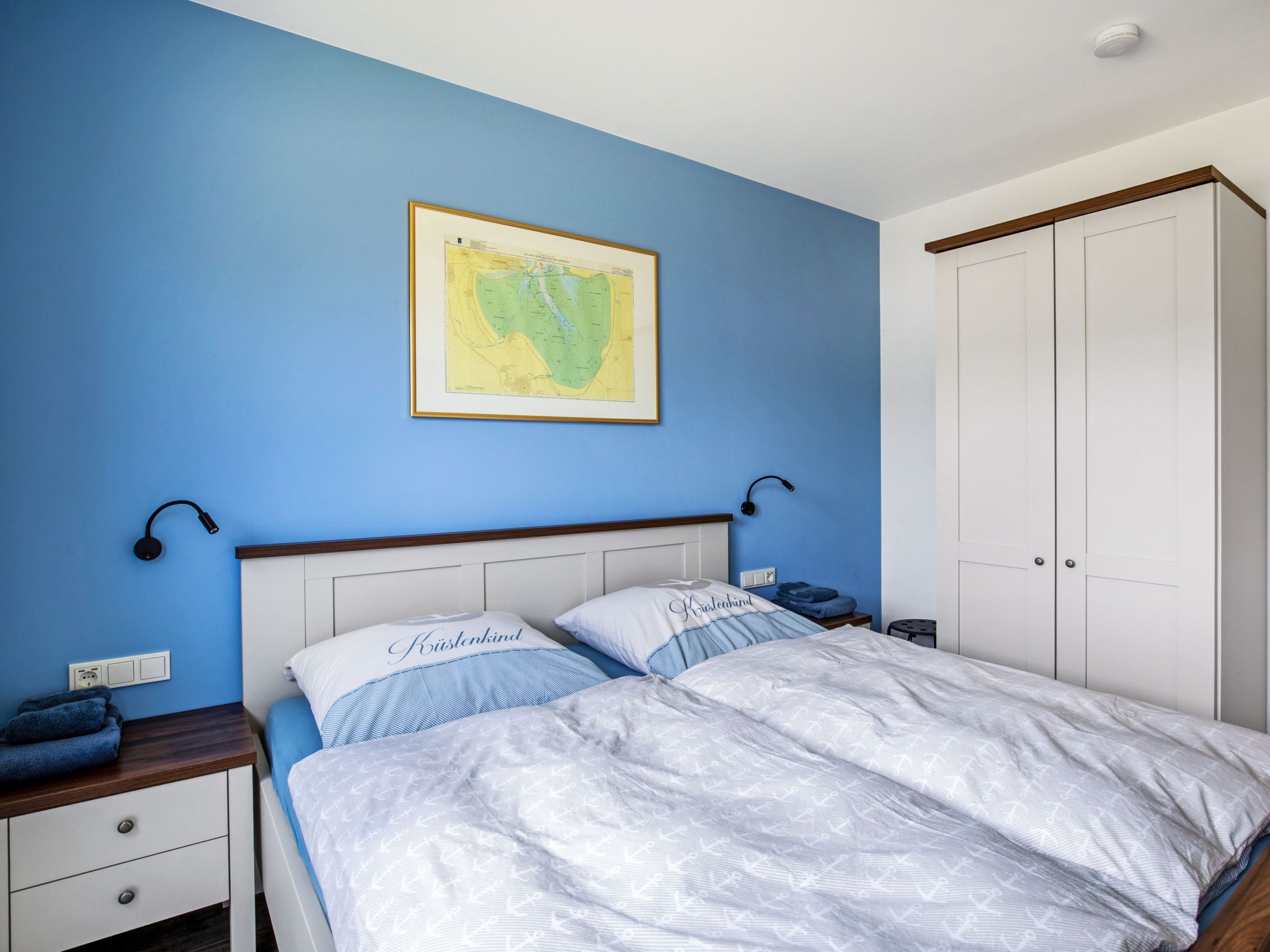 Une chambre à coucher avec un lit, une table de chevet, une armoire et une carte accrochée au mur.