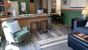 A modern kitchen with a bar area, green walls, and a dining area with a table and chairs.