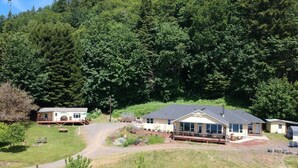 A cabin-style hotel with a large deck and multiple rooms, surrounded by dense forest.