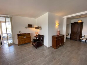 Un vaste espace de vie agrémenté d’un meuble en bois, d’un fauteuil en cuir et d’une bibliothèque adossée au mur.