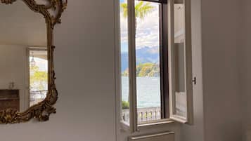 Una stanza con un grande specchio decorato, una finestra vista lago e montagne, e un termosifone.