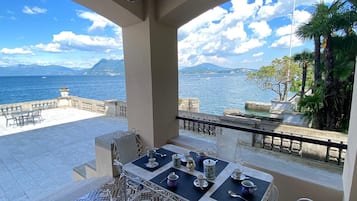 Une terrasse avec une table préparée pour le thé, d’où l’on peut admirer un plan d’eau et des montagnes.