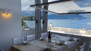 A dining area with a table set for four, overlooking a lake with mountains in the background. - Wonderful Stresa apartment on the lake in Stresa (Stresa)