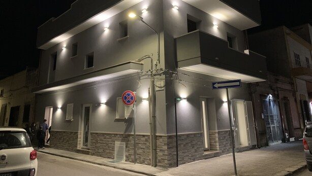 Un immeuble à plusieurs étages doté d’une architecture moderne, avec un balcon au deuxième étage et une entrée au niveau du rez-de-chaussée.
