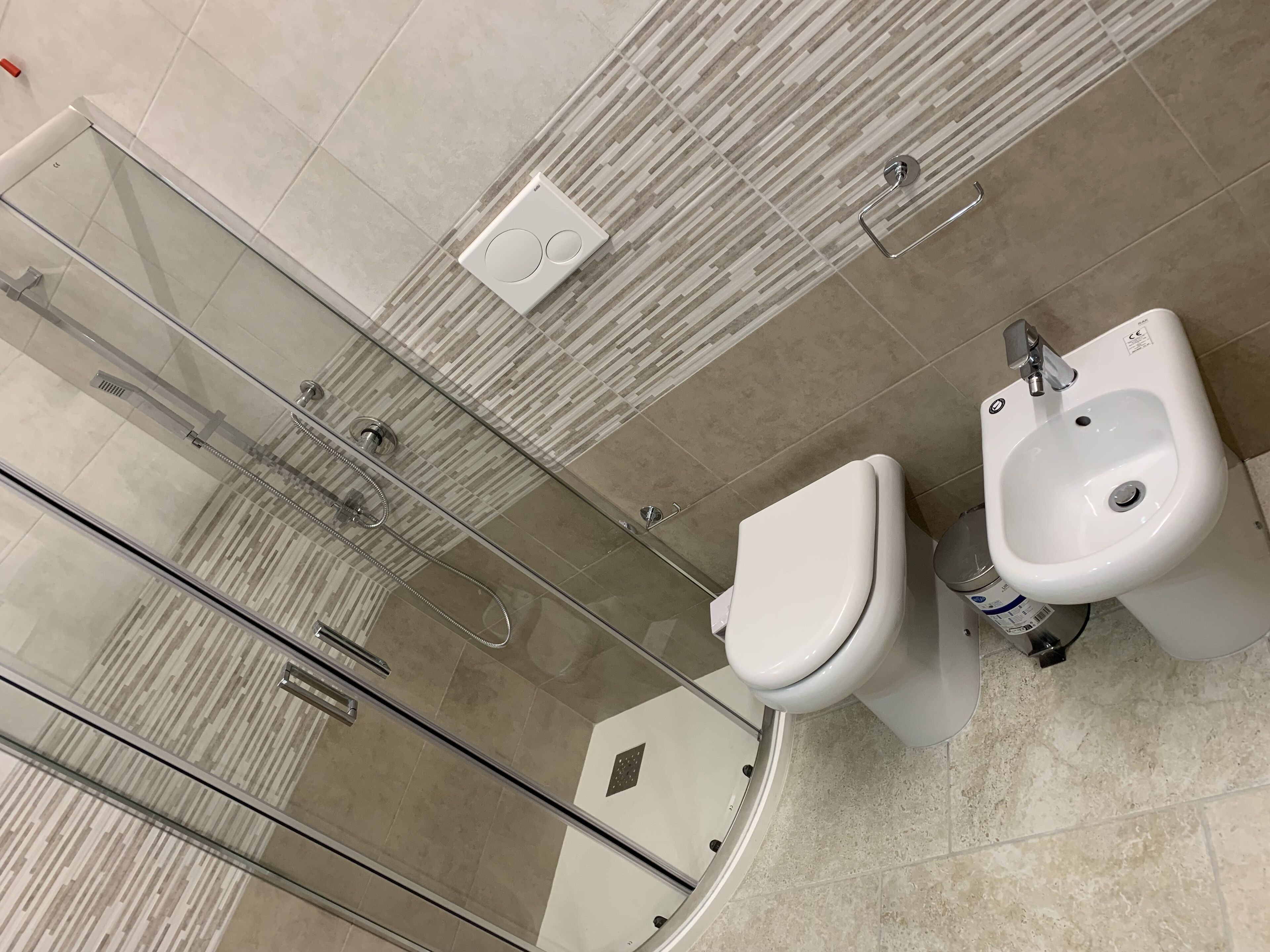 A modern bathroom with a glass-enclosed shower, a toilet, and a bidet.