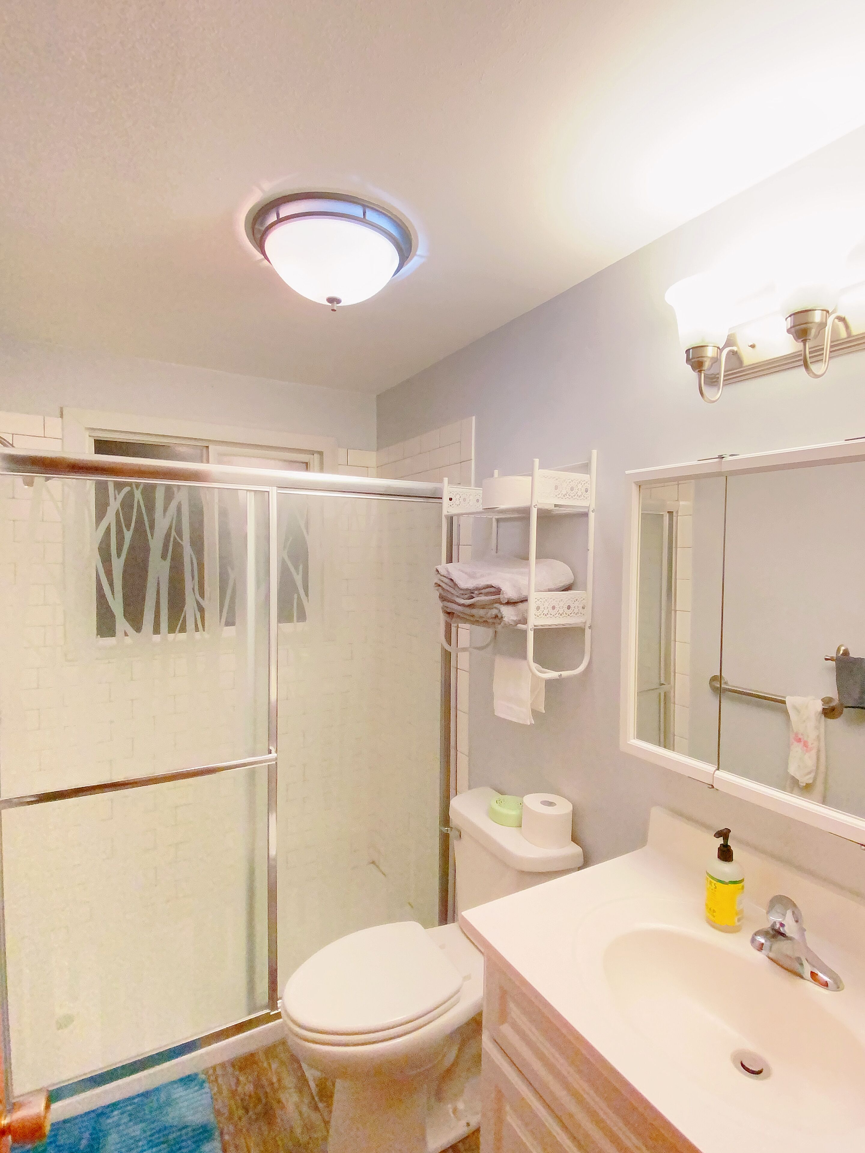 A bathroom with a shower, toilet, sink, and a mirror.
