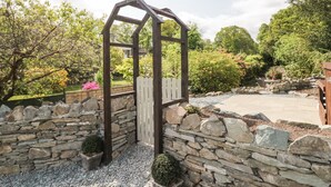 Un muro in pietra con una struttura in legno a pergola.