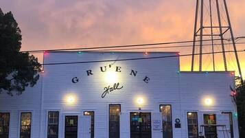 A building with 'GRUENE Hall' signage, a water tower, and a wet ground reflecting lights.