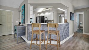 Une cuisine moderne dotée d’un îlot central, de tabourets de bar et d’une petite table d’appoint.