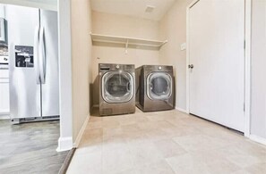 Convenient laundry facilities with two front-loading washing machines and a nearby kitchenette area.