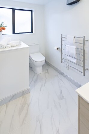 Un bagno moderno con un WC bianco, pavimento in marmo e un porta asciugamani.