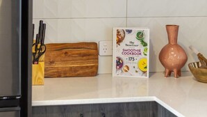 Eine Küche mit dunklen Holzschränken, einer weißen Arbeitsplatte, einem Kochbuch und einer Vase.
