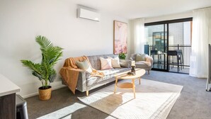Ein modernes Wohnzimmer mit einer Couch, einem Couchtisch und einer Topfpflanze.