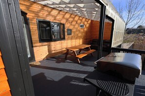 En udendørs patio med træbænke og grill.