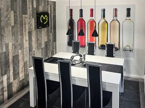 Une cuisine moderne avec un plan de travail blanc, des chaises noires et un mur en bois.