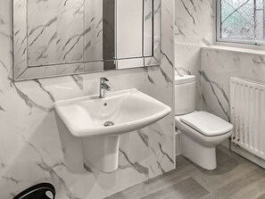 Une salle de bain avec un lavabo en marbre, des toilettes et une fenêtre en verre dépoli.