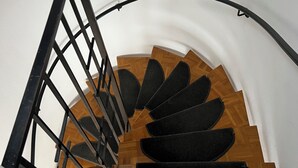 A spiral staircase with wooden steps and a black metal railing.