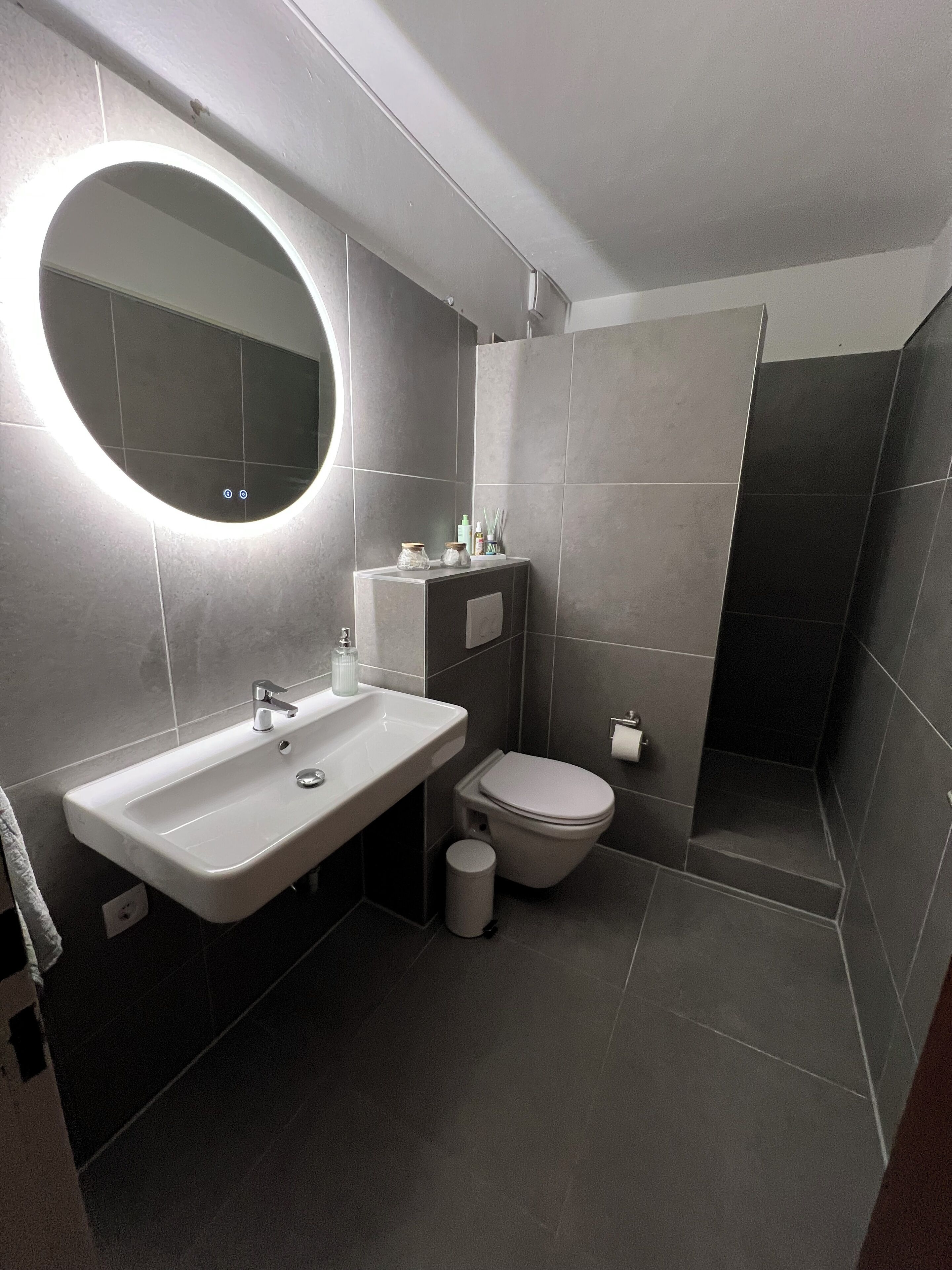 Een moderne badkamer met een wit wastafel, toilet en douche.