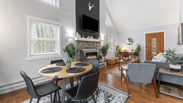 Un salon spacieux avec une cheminée, un coin repas avec une table ronde et des chaises, et un espace détente avec un canapé et des fauteuils.