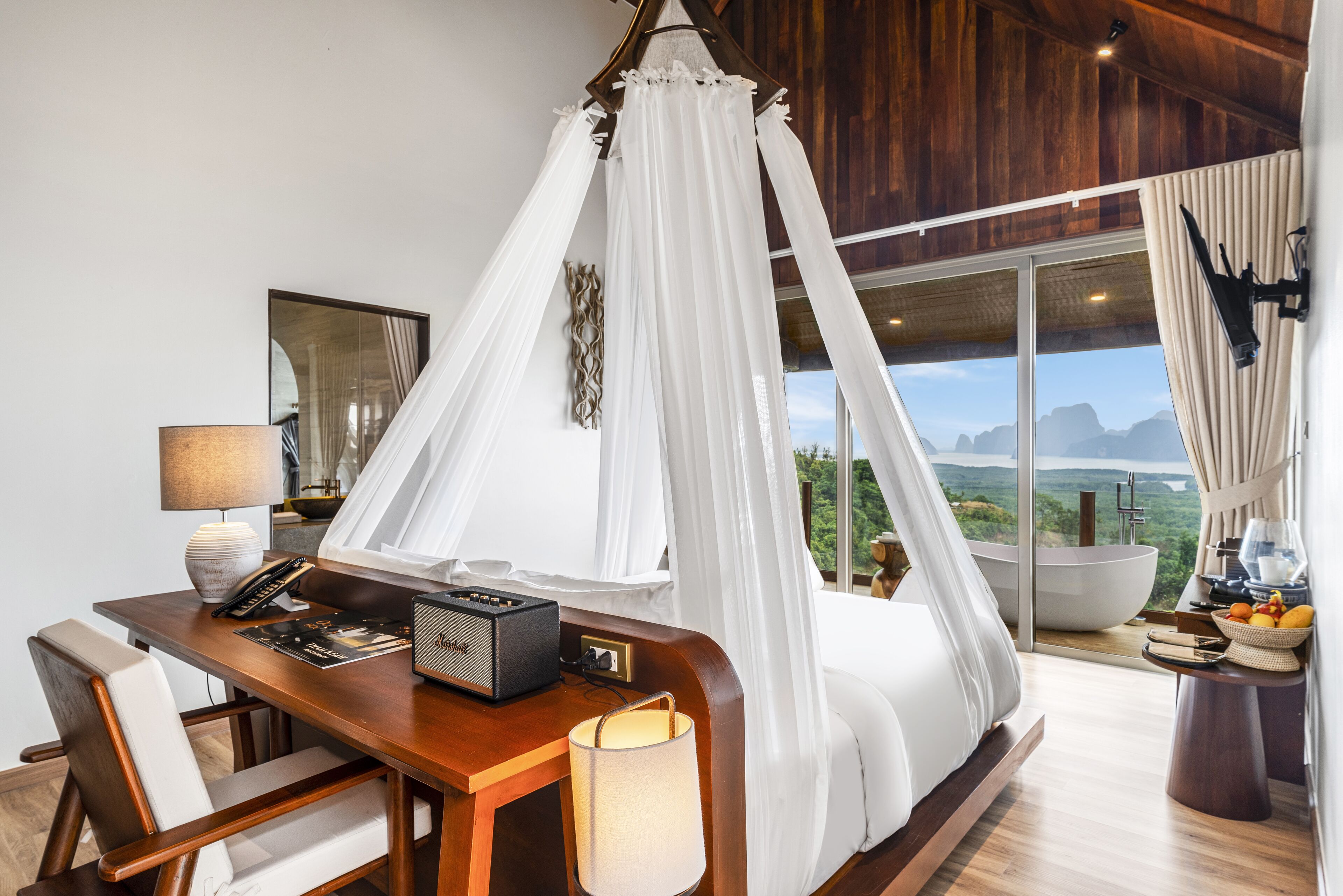 Un dormitorio con cama con dosel, un escritorio con radio, una lámpara y vistas a las montañas.