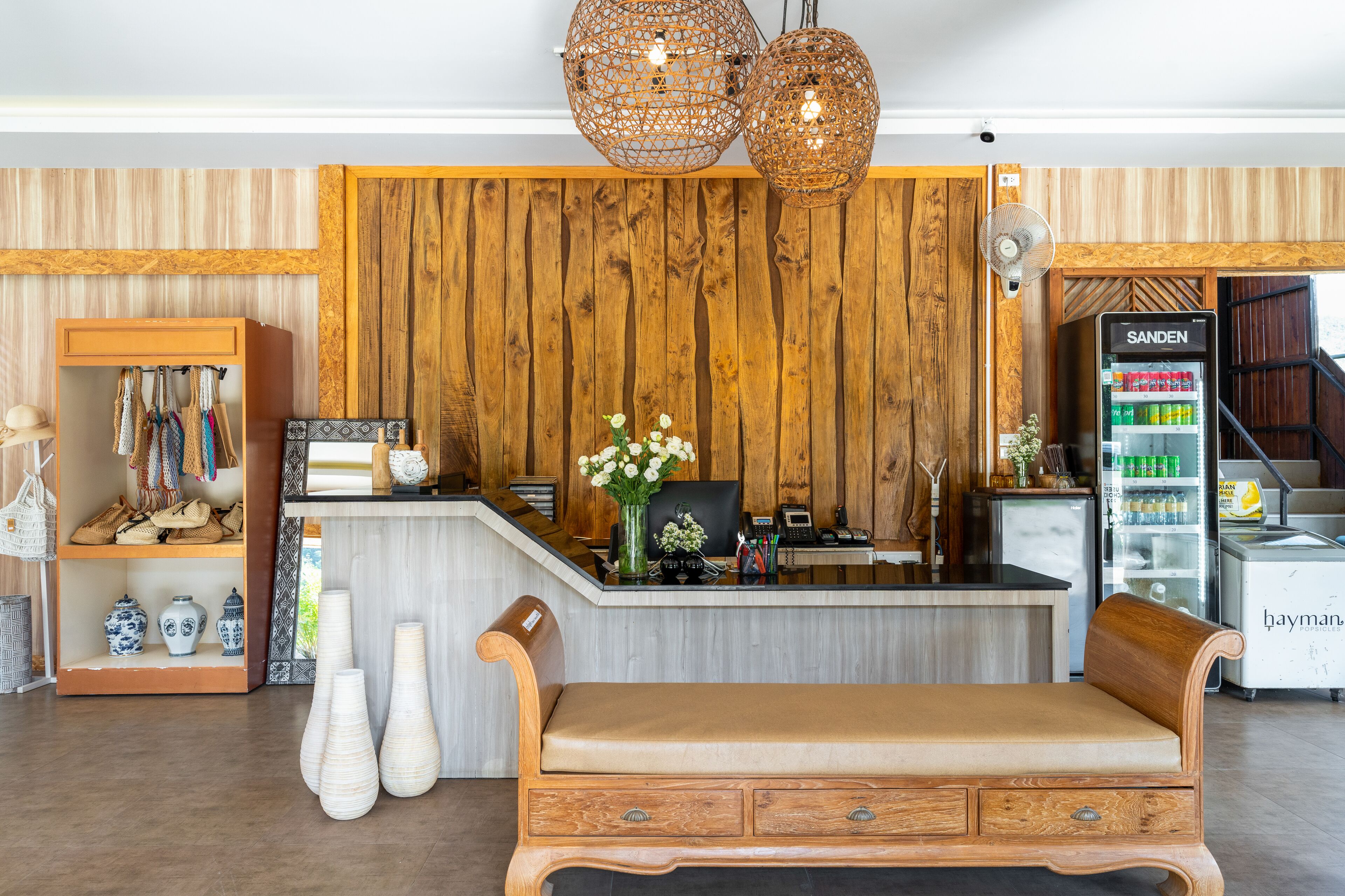 A reception area with a wooden wall, a reception desk, a bench, and a refrigerator.