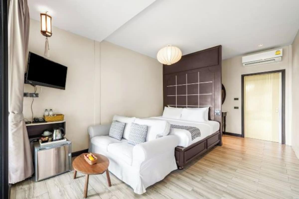 Una habitación de hotel moderna con cama, sofá, una mesita, televisión y aire acondicionado.