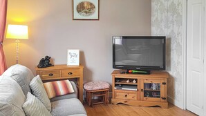 A living room with a sofa, a TV, a wooden cabinet, and a small table.