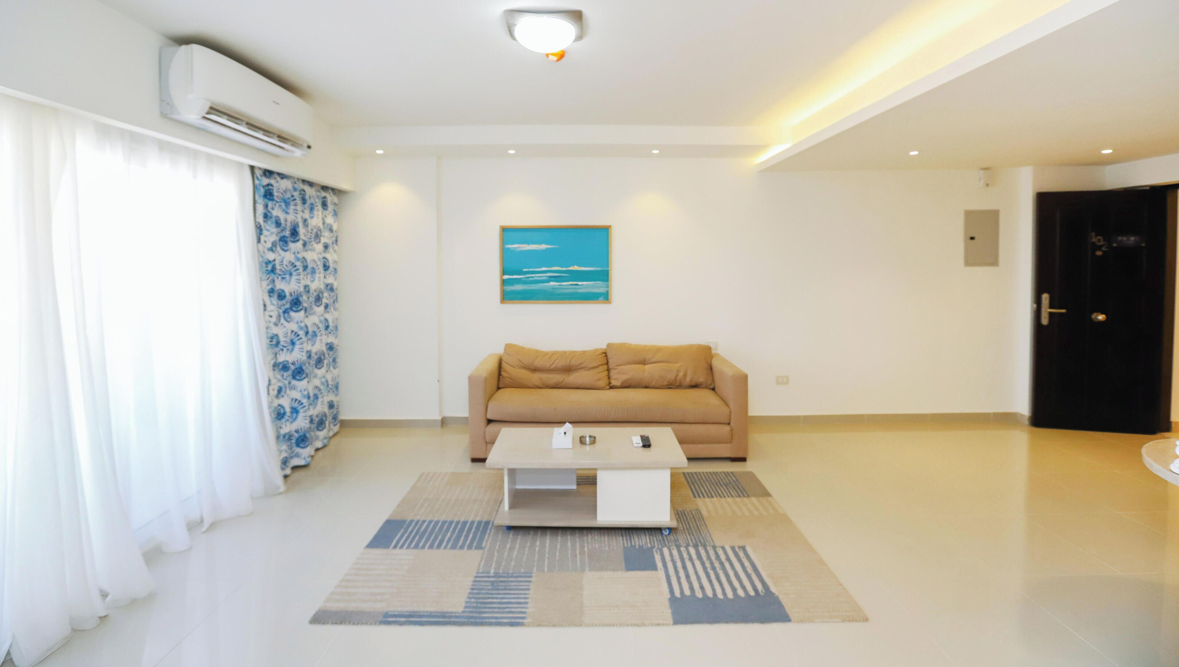 Una sala de estar moderna con un sofá color beige, una mesa de centro y un tapete estampado.