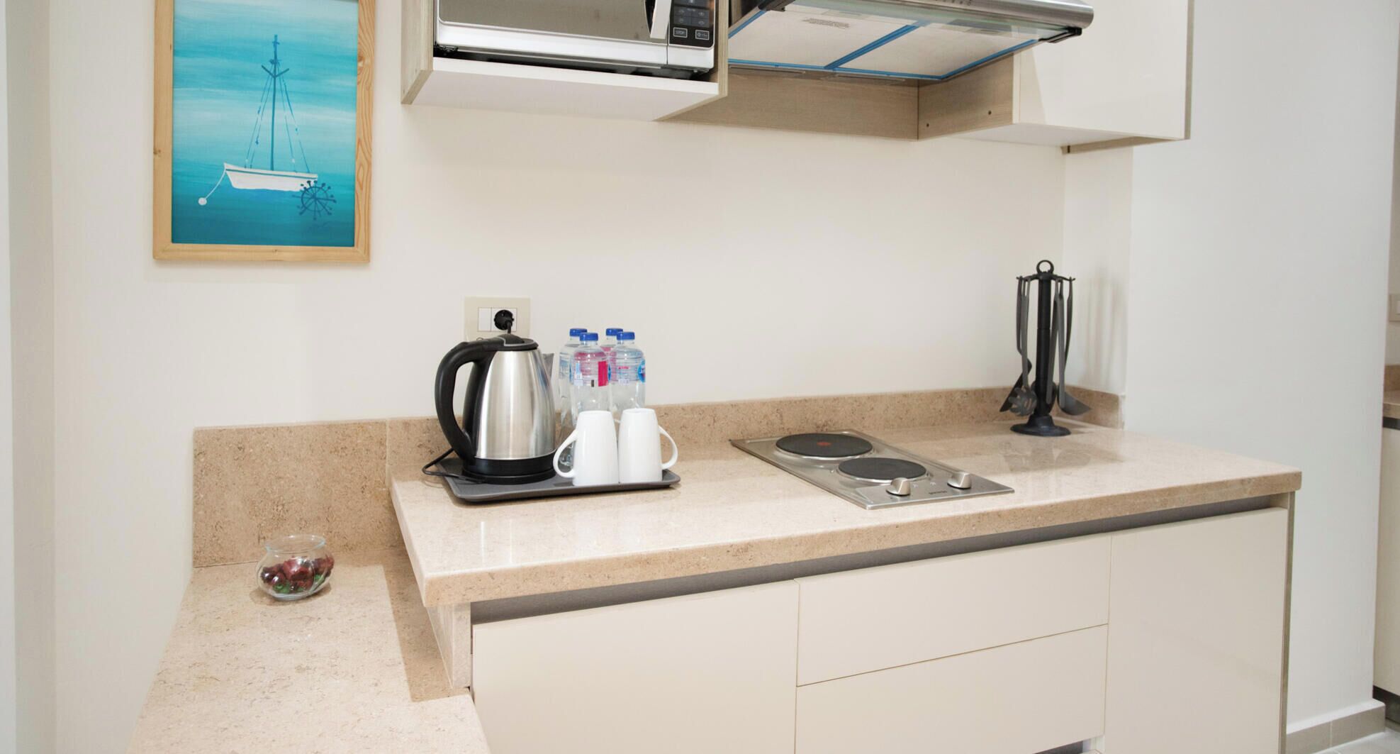 Una kitchenette con cafetera, botellas de agua y tetera.