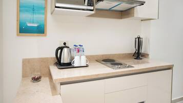 Una kitchenette con cafetera, botellas de agua y tetera.