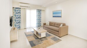 A modern living room with a beige sofa, a coffee table, and patterned curtains. - Prime Residence New Alamein (El Alamein)