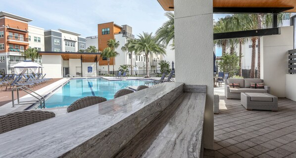 A swimming pool area with lounge chairs and a covered seating area.