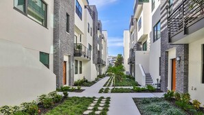 Un edificio residencial moderno con un patio central, que incluye un sendero y vegetación.