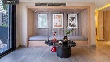 Un intérieur moderne avec une table ronde noire, un banc rembourré de couleur grise et des œuvres d’art abstraites encadrées accrochées au mur.
