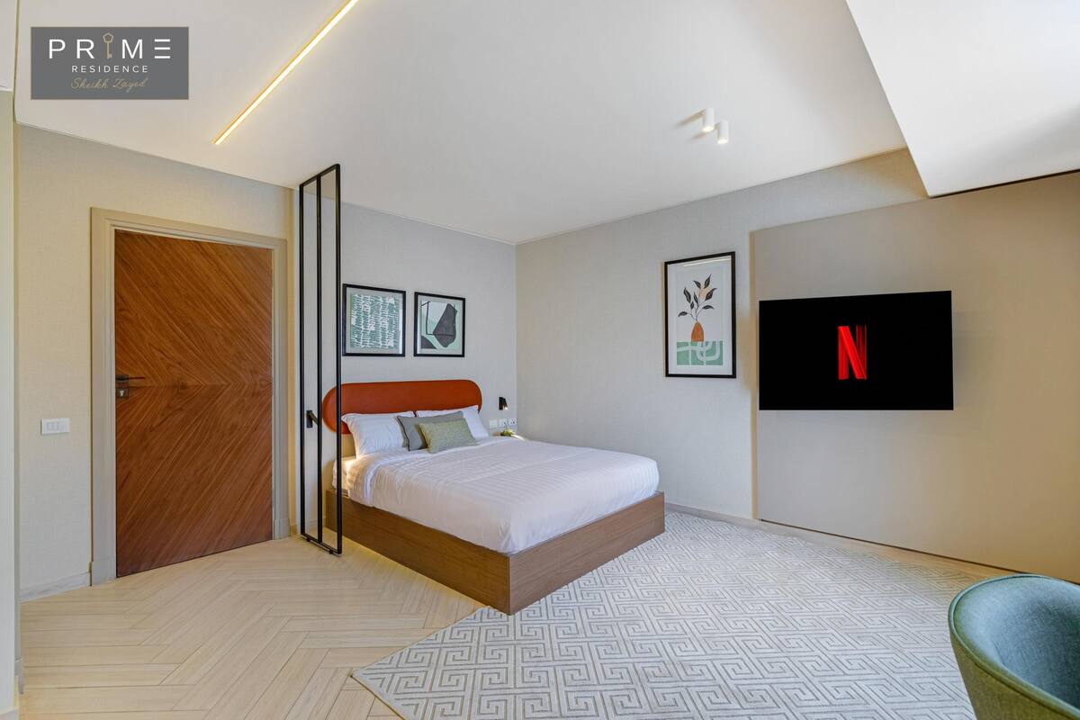 A modern bedroom with a bed, a TV, and a door.