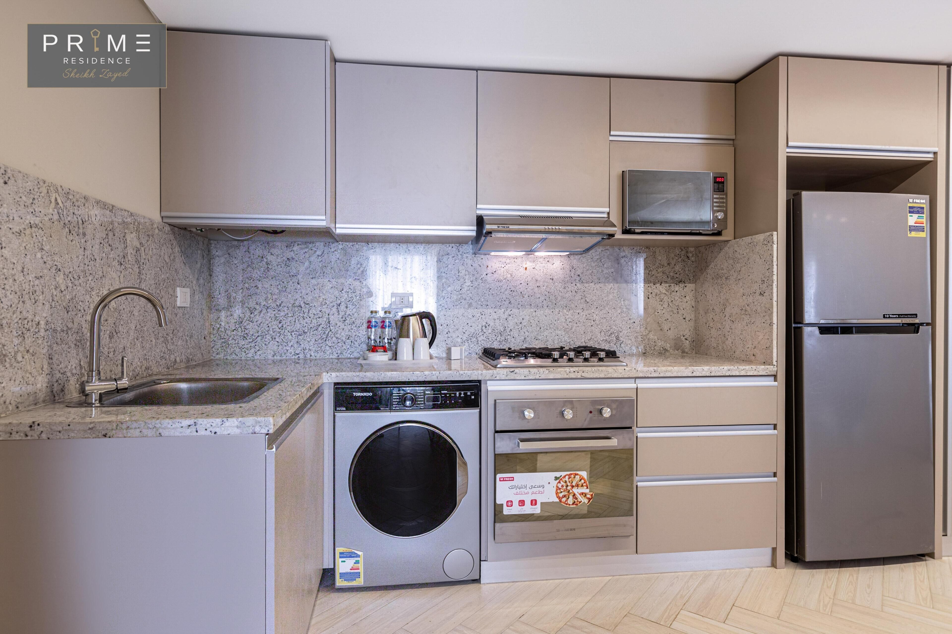 A modern kitchen with a built-in washing machine, oven, microwave, and refrigerator.