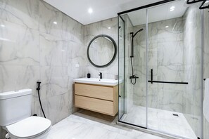 A modern bathroom with a toilet, vanity, and a glass-enclosed shower. - Prime Residence Sheikh Zayed (Sheikh Zayed City)