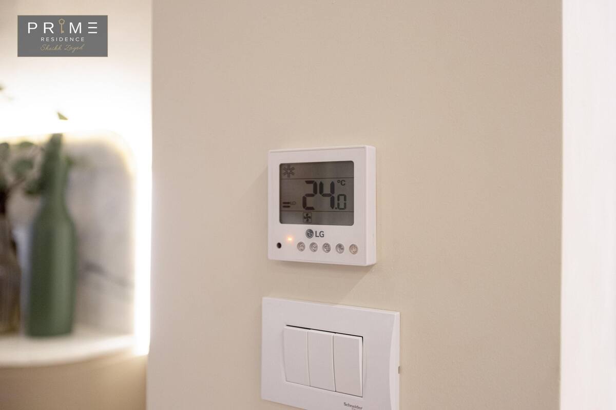 A thermostat and a light switch on a wall.