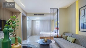 A modern hotel room with a sofa, a round coffee table, a TV, and a large window with curtains. - Prime Residence Sheikh Zayed (Sheikh Zayed City)