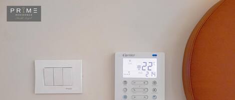 A wall with three thermostats and a light switch.
