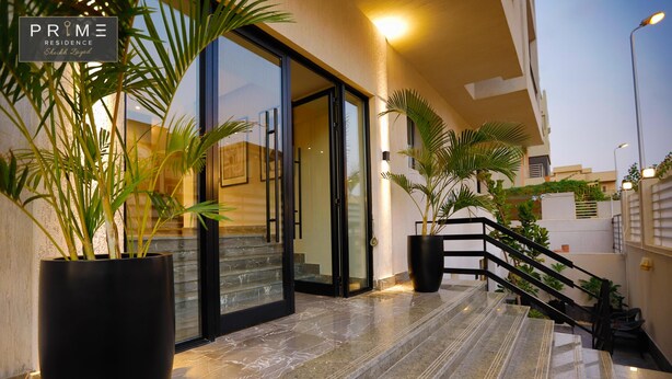A modern hotel entrance with a glass door, a marble staircase, and potted plants. - Prime Residence Sheikh Zayed (Sheikh Zayed City)