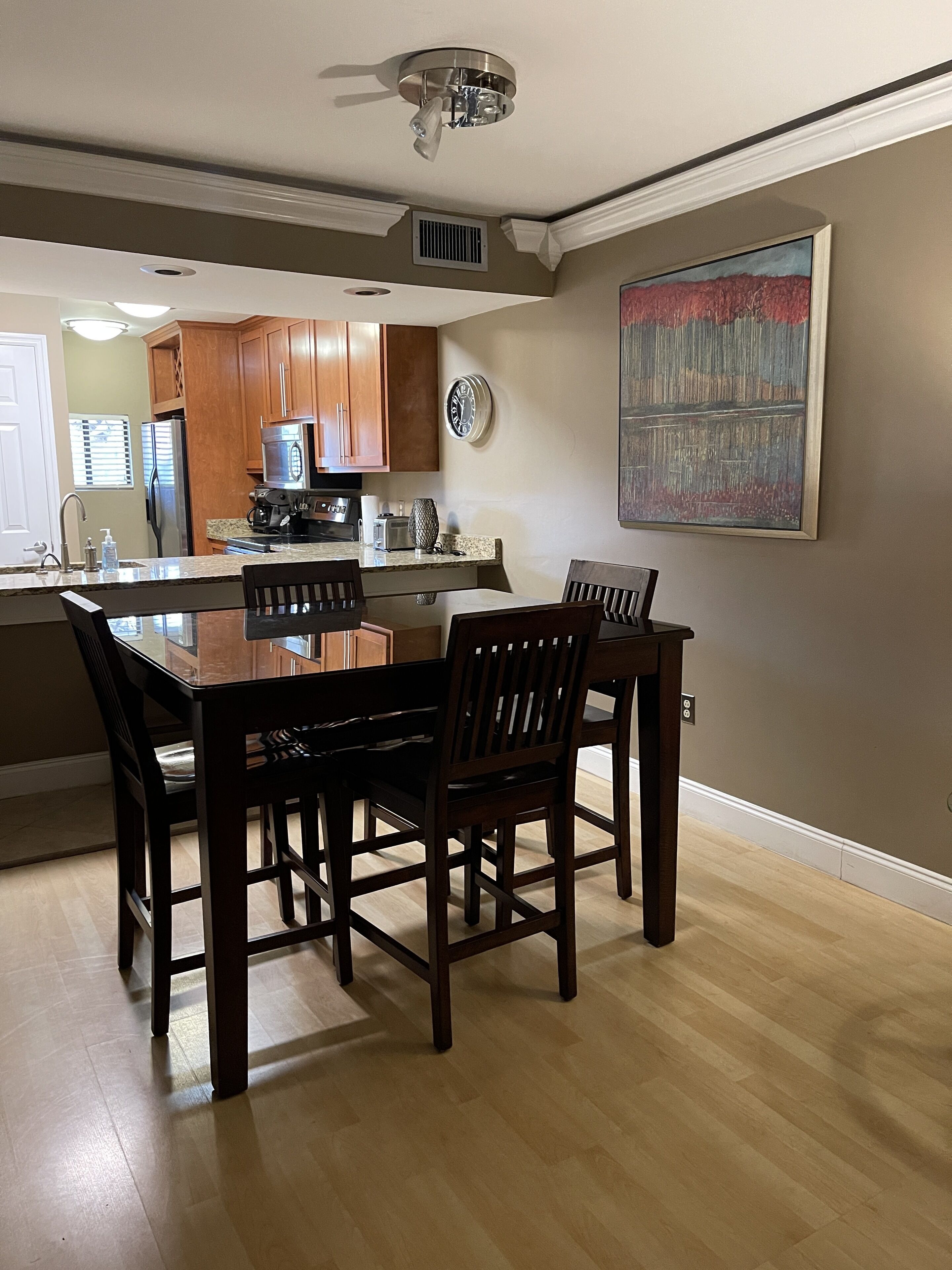 A modern kitchen with wooden cabinets, a granite countertop, and a dining area with a wooden table and chairs.