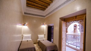 A room with two beds, a balcony with a decorative railing, and a view of a building with arches. - Riad Minami (Marrakech)
